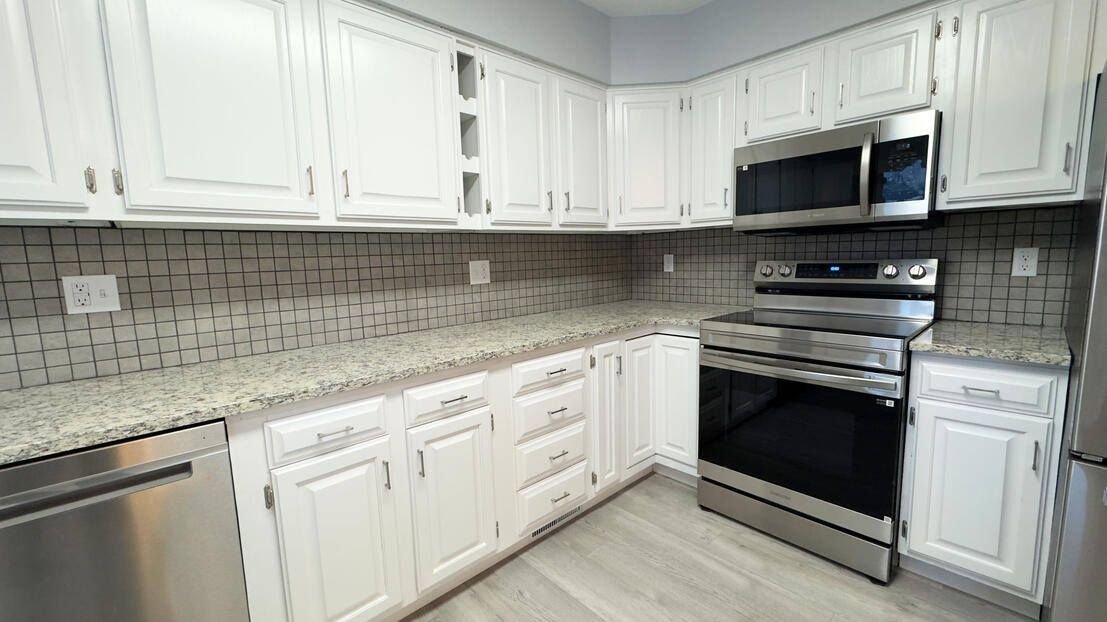 Professional kitchen cabinet painting and installation with modern grey stone backsplash and quartz countertops in a Bismarck renovation.