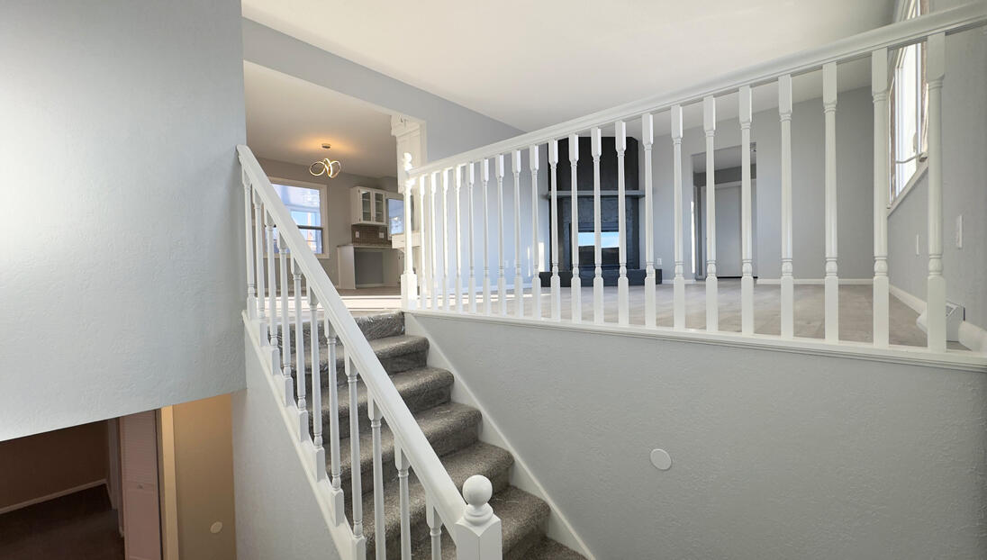 Renovated split-level entryway featuring crisp white painted balusters and railings, fresh light grey walls, and new carpeting.