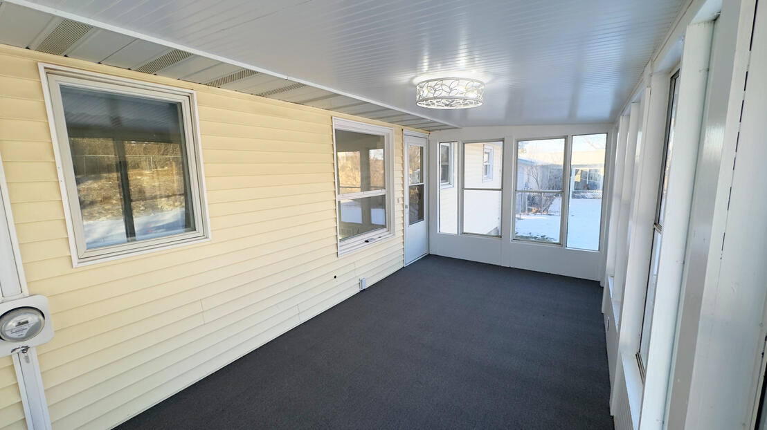 Bright sunroom renovation with freshly painted white window trim, light yellow interior walls, and contrasting dark grey flooring by Will Contracting