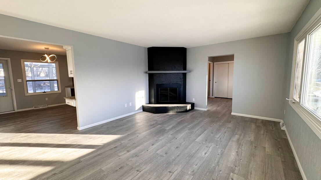 Modern Family room renovation with a professionally painted black accent fireplace, smooth grey walls, and new wood-look flooring.